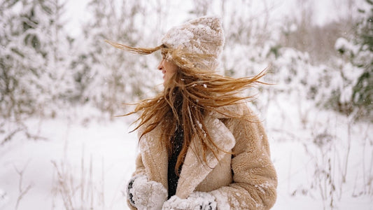 Frau im Schnee mit warmer Kleidung – Symbolbild für Hautschutz und Pflege bei Kälte und trockener Winterhaut